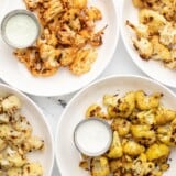 Four plates full of roasted cauliflower with dipping sauce.