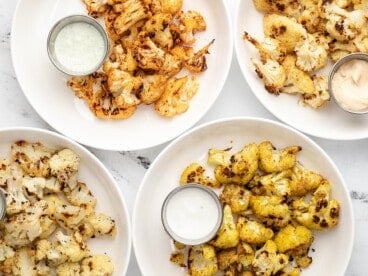 Four plates full of roasted cauliflower with dipping sauce.