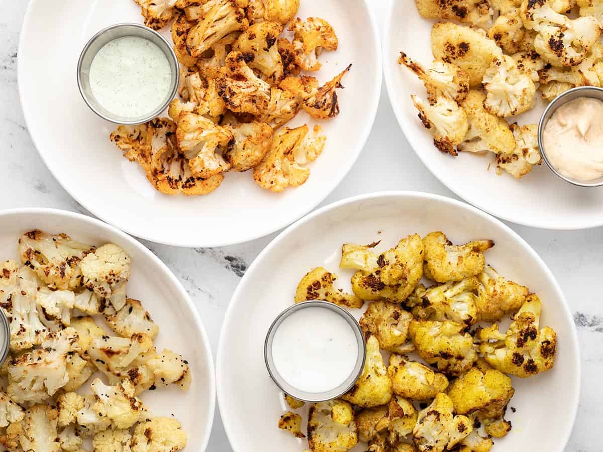 Four plates full of roasted cauliflower with dipping sauce. 