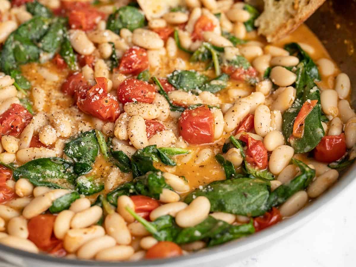 Close up side view of saucy white beans in the skillet. 