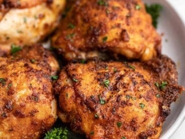 Close up side view of air fryer chicken thighs on a plate.