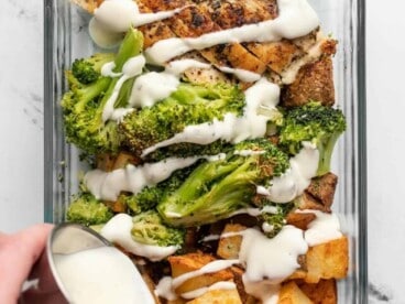 Overhead view of a ranch chicken meal prep container with ranch dressing being drizzled over top.