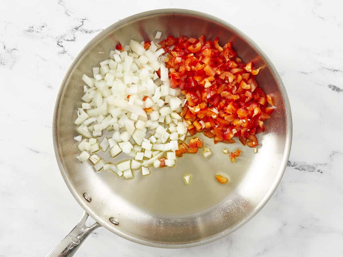 Onions and peppers in a silver pan.