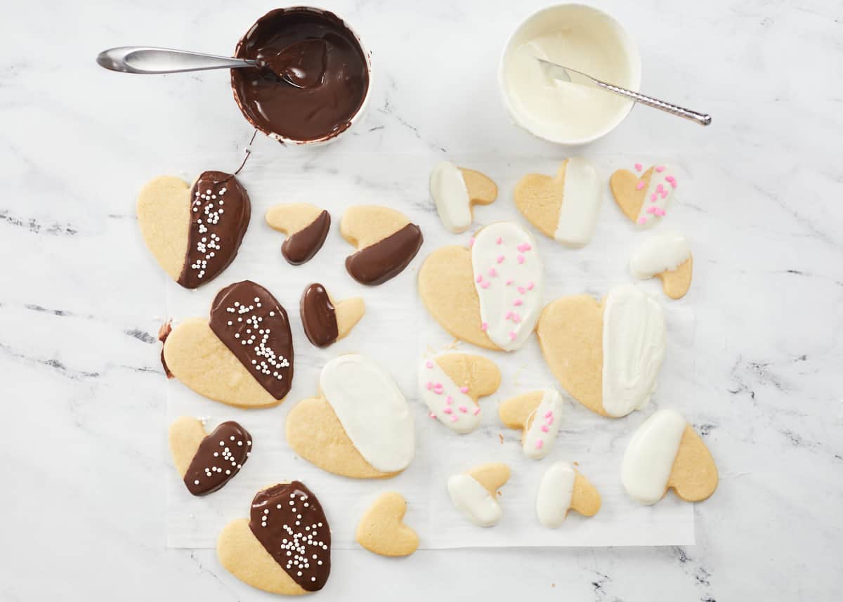 Vue aérienne de biscuits de la Saint-Valentin trempés dans du chocolat blanc et au lait et décorés de vermicelles.