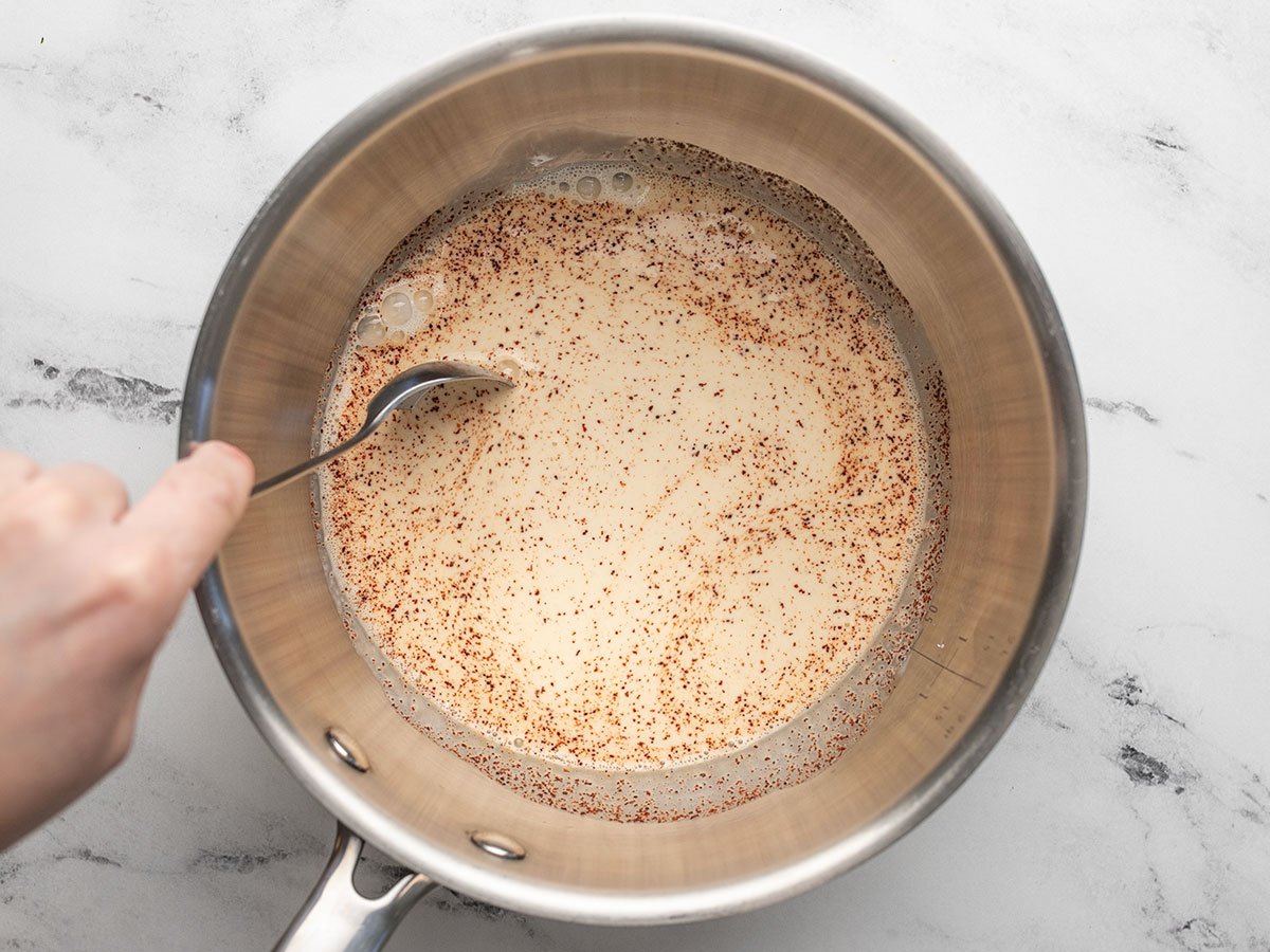 Evaporated milk and spices in a saucepot being stirred. 