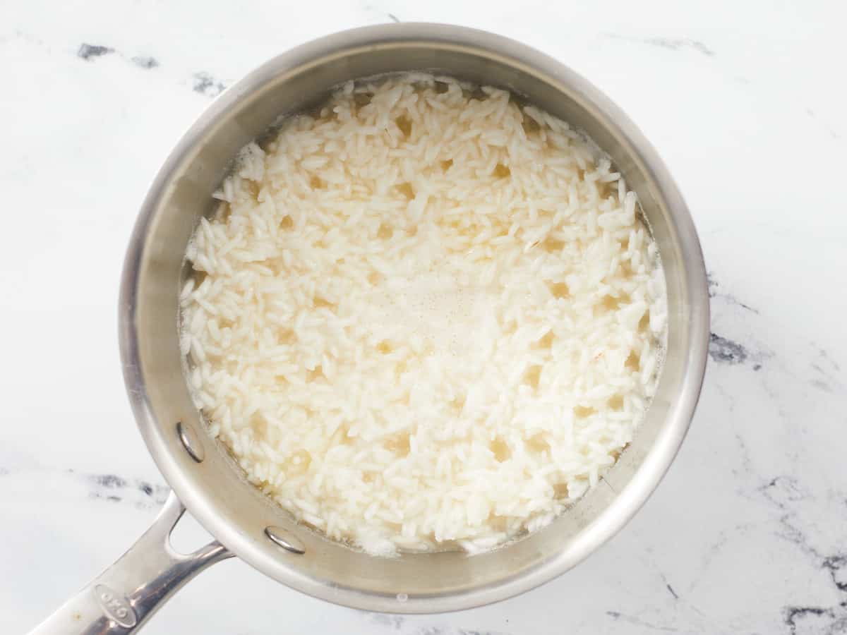Overhead shot of rice with surface steam vents in a pot.