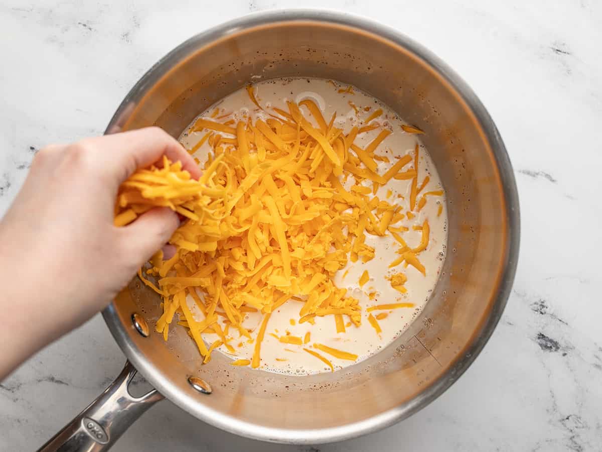 Shredded cheese being added to the evaporated milk. 