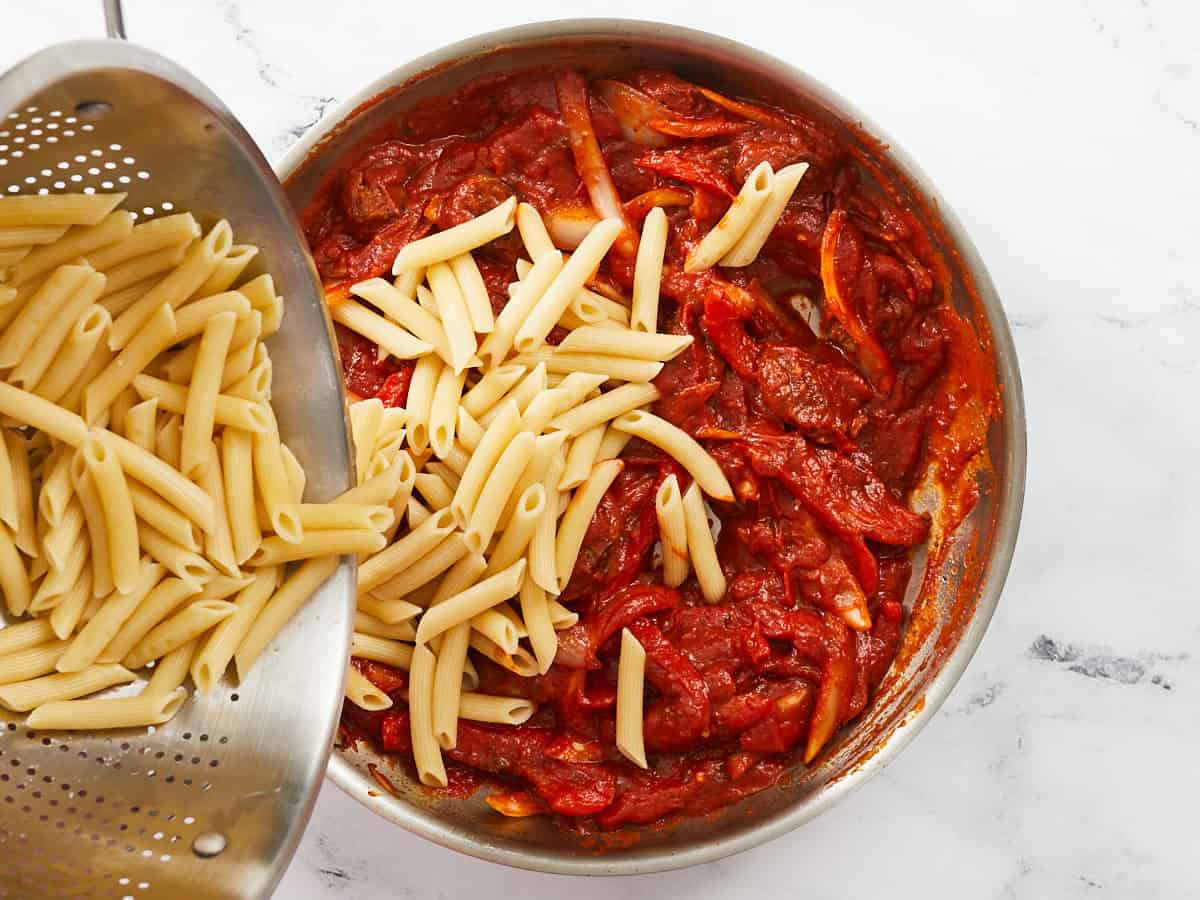 Adding cooked penne to the skillet.