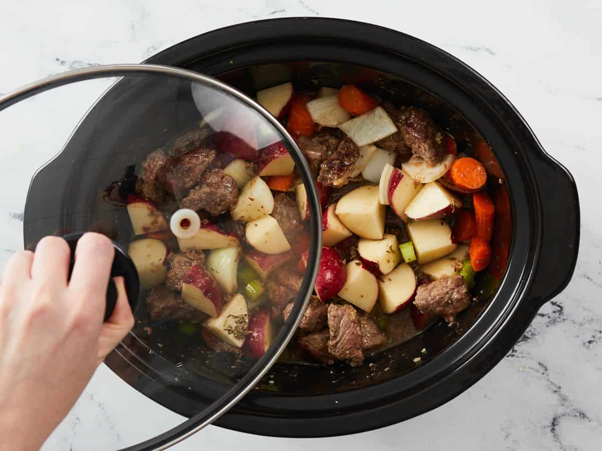 Slow cooker being covered with a lid. 