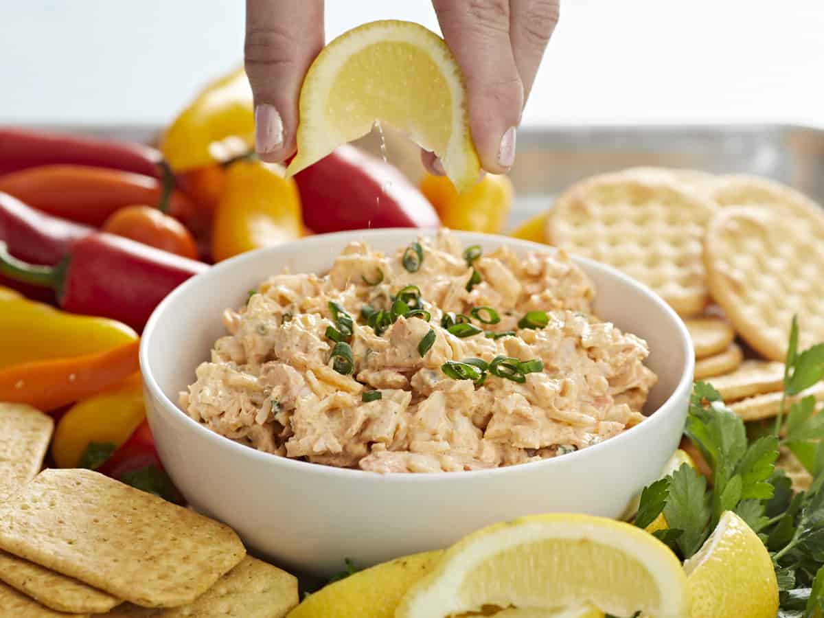 Hand squeezing lime on crab dip.