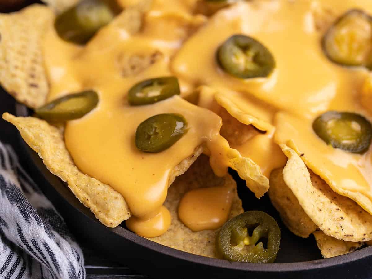 close up side view of a plate of nachos with jalapeños.