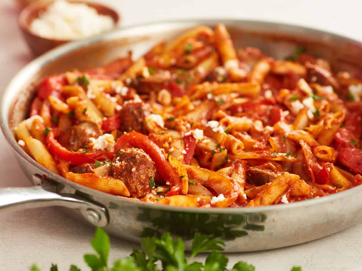 Side view of pasta with sausage and peppers in the skillet.