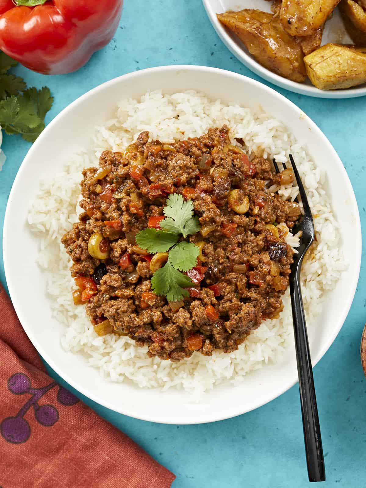 Picadillo served over white rice in a white bowl.