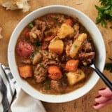 Overhead view of a bowl of beef stew with a spoon.