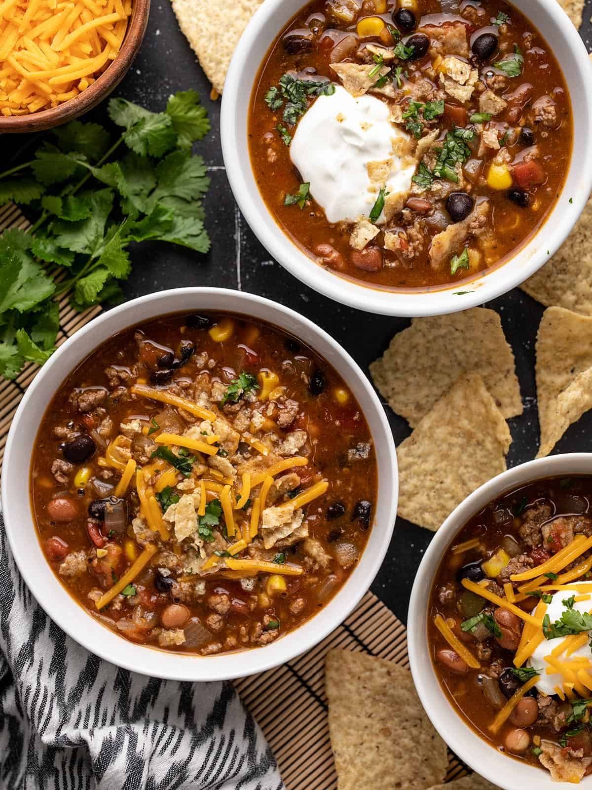 Three bowls of taco soup with different toppings.