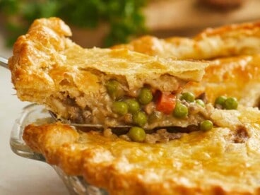 Side shot of a slice of veggie pot pie being removed from the pie dish.
