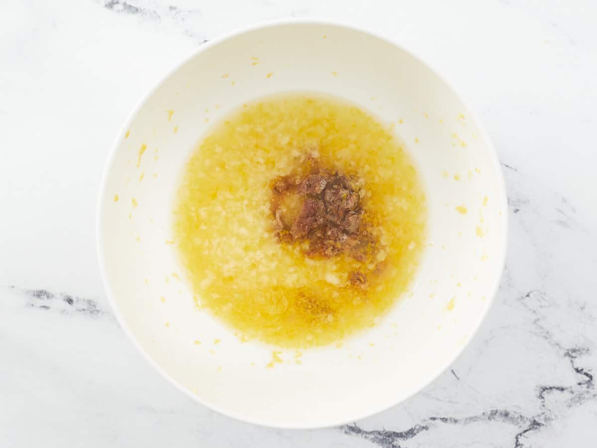 Jugo de limón, ralladura, anchoas, ajo y pimienta en un tazón.