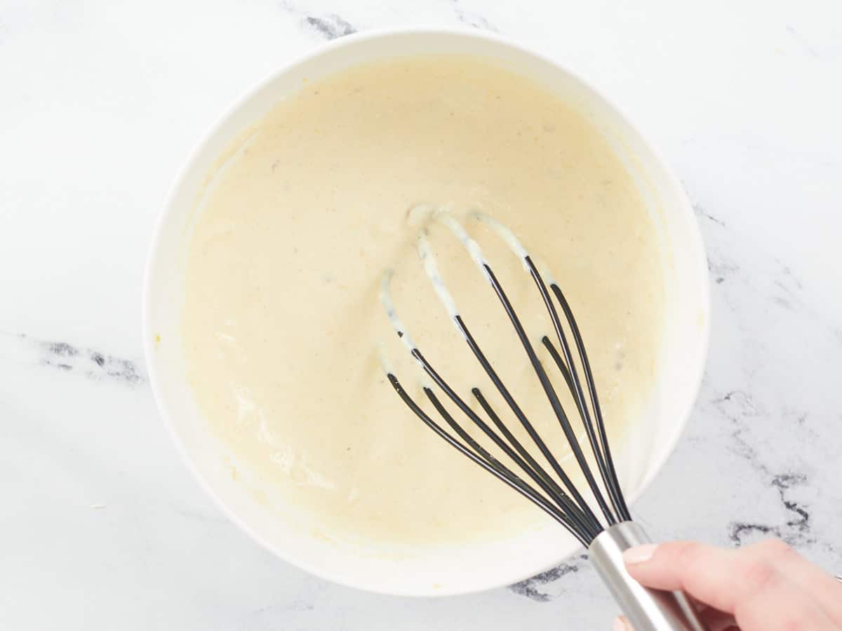 Whisked Caesar dressing in a bowl with a whisk.