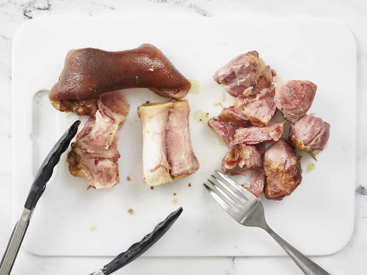 Removing ham meat from the bone with a knife and fork. 