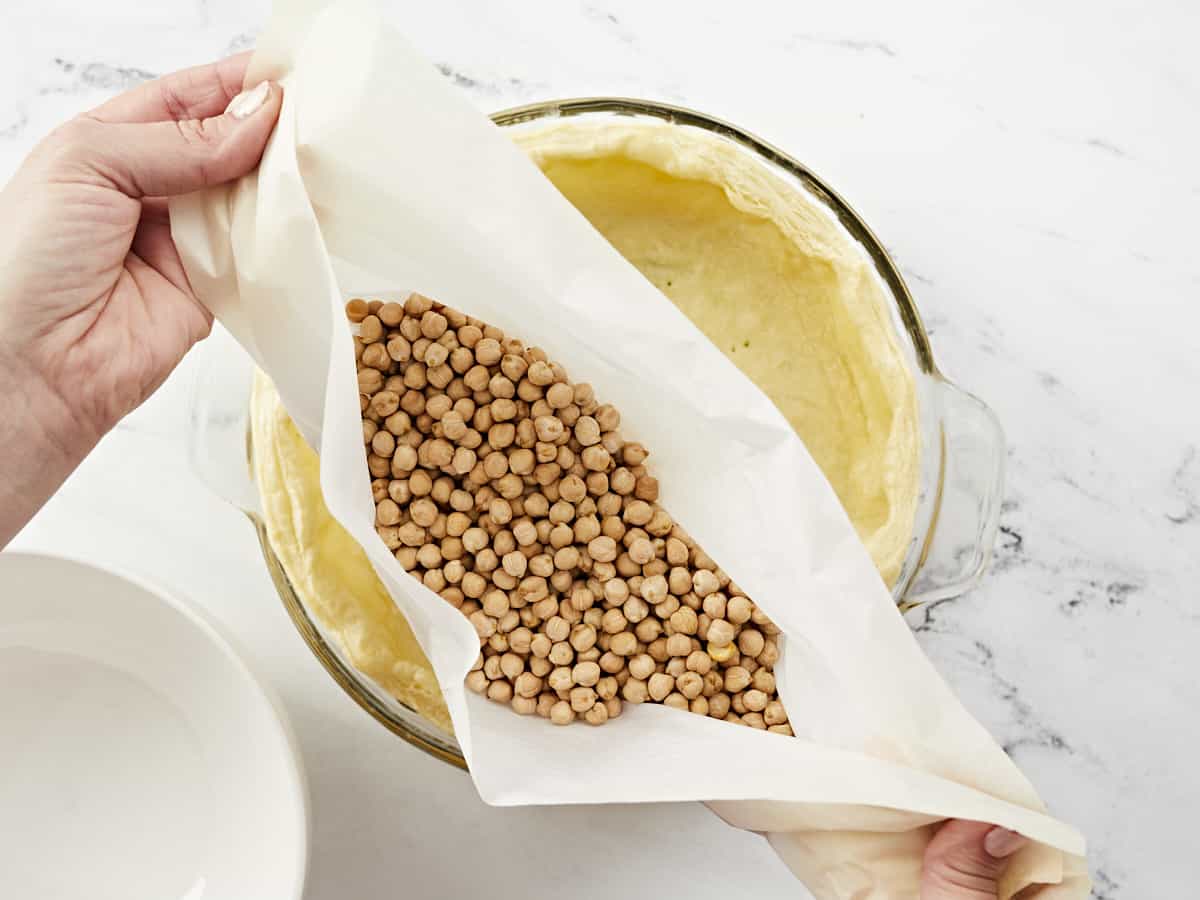 Overhead shot of beans being removed from par-baked crust.