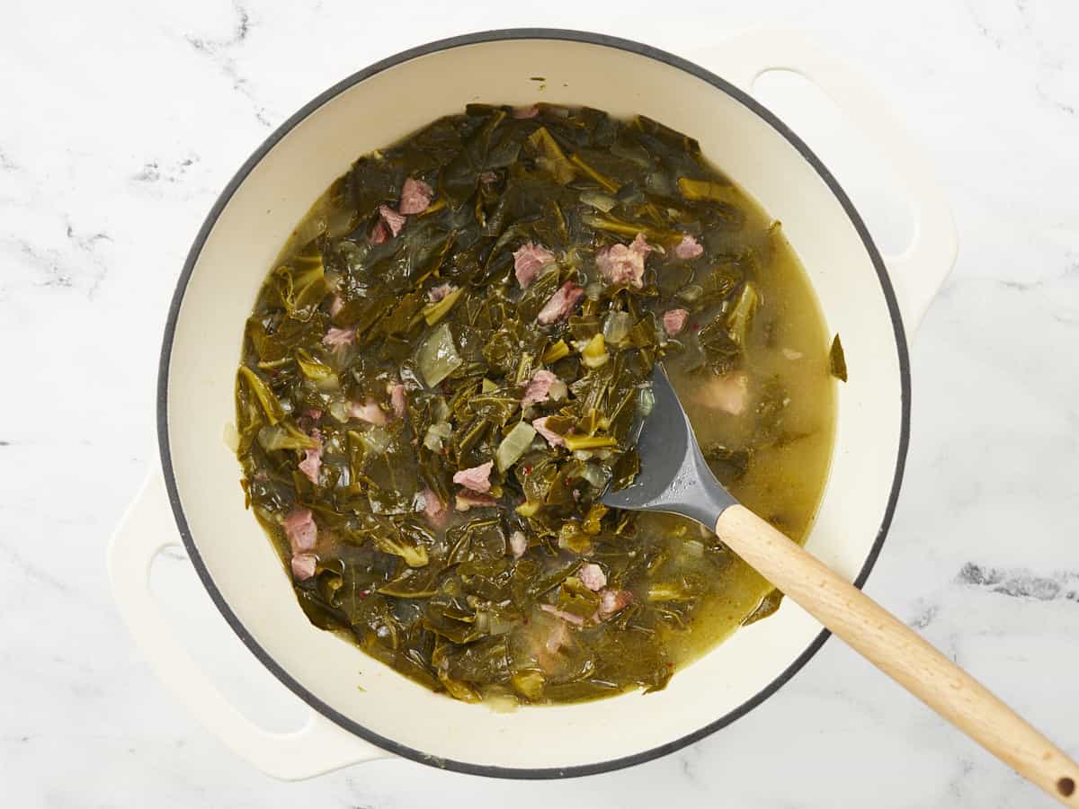 Finished collard greens in the pot with a spoon.