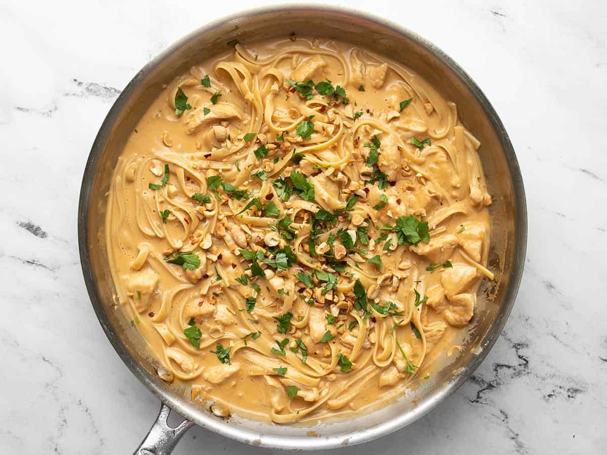 Peanut noodles in the skillet topped with chopped peanuts and cilantro.