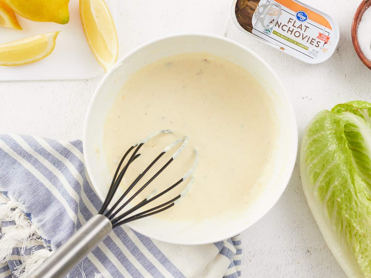 Homemade Caesar dressing in a bowl with a whisk.