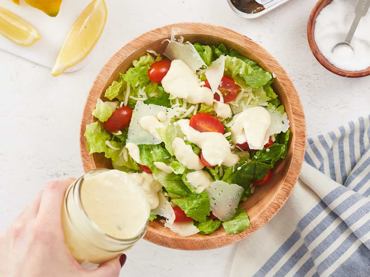 Se vierte el aderezo César sobre una ensalada.