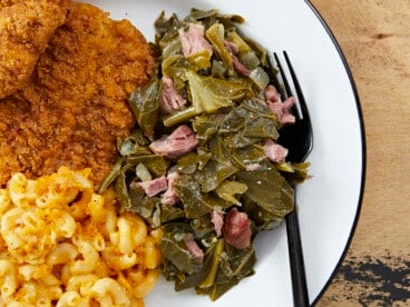 Overhead view of collard greens on a plate with chicken and mac and cheese.