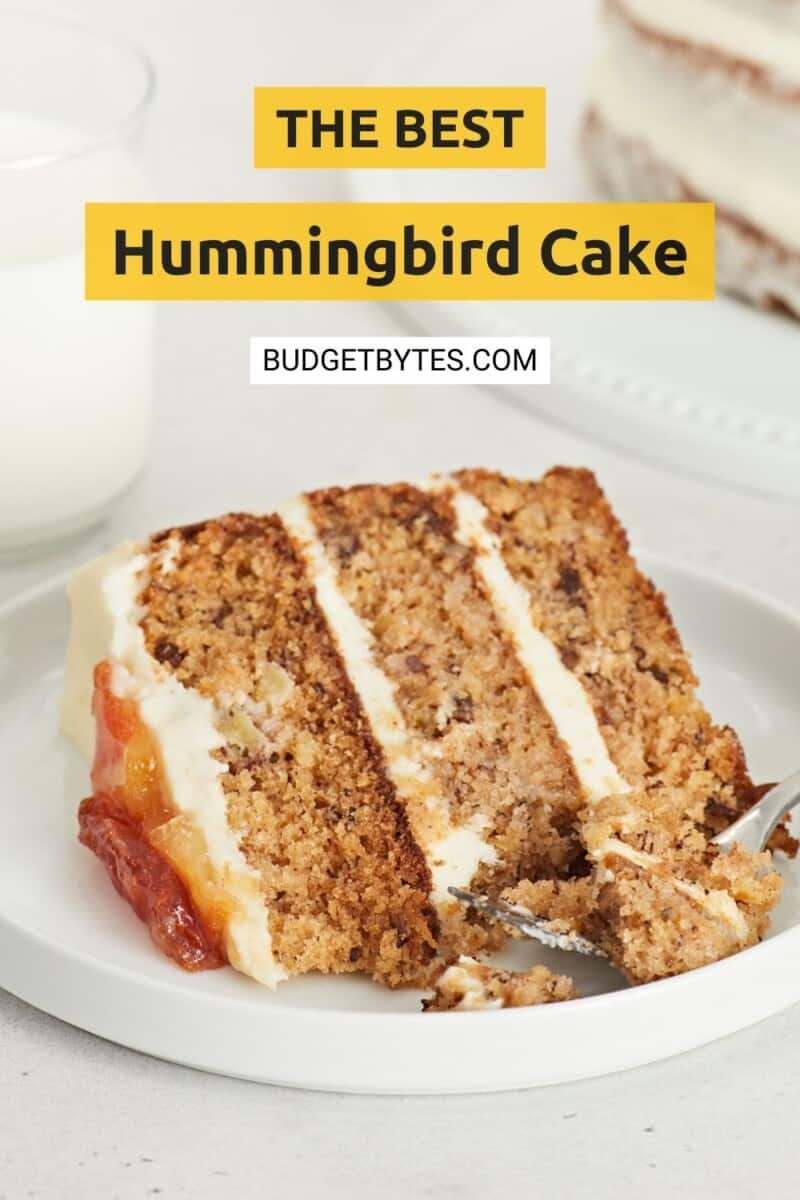 Slice of Hummingbird Cake on a white plate with a fork in it.