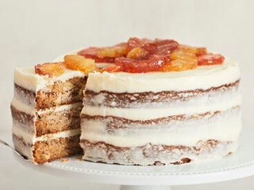 Side shot of Hummingbird Cake with a slice being taken out of it.