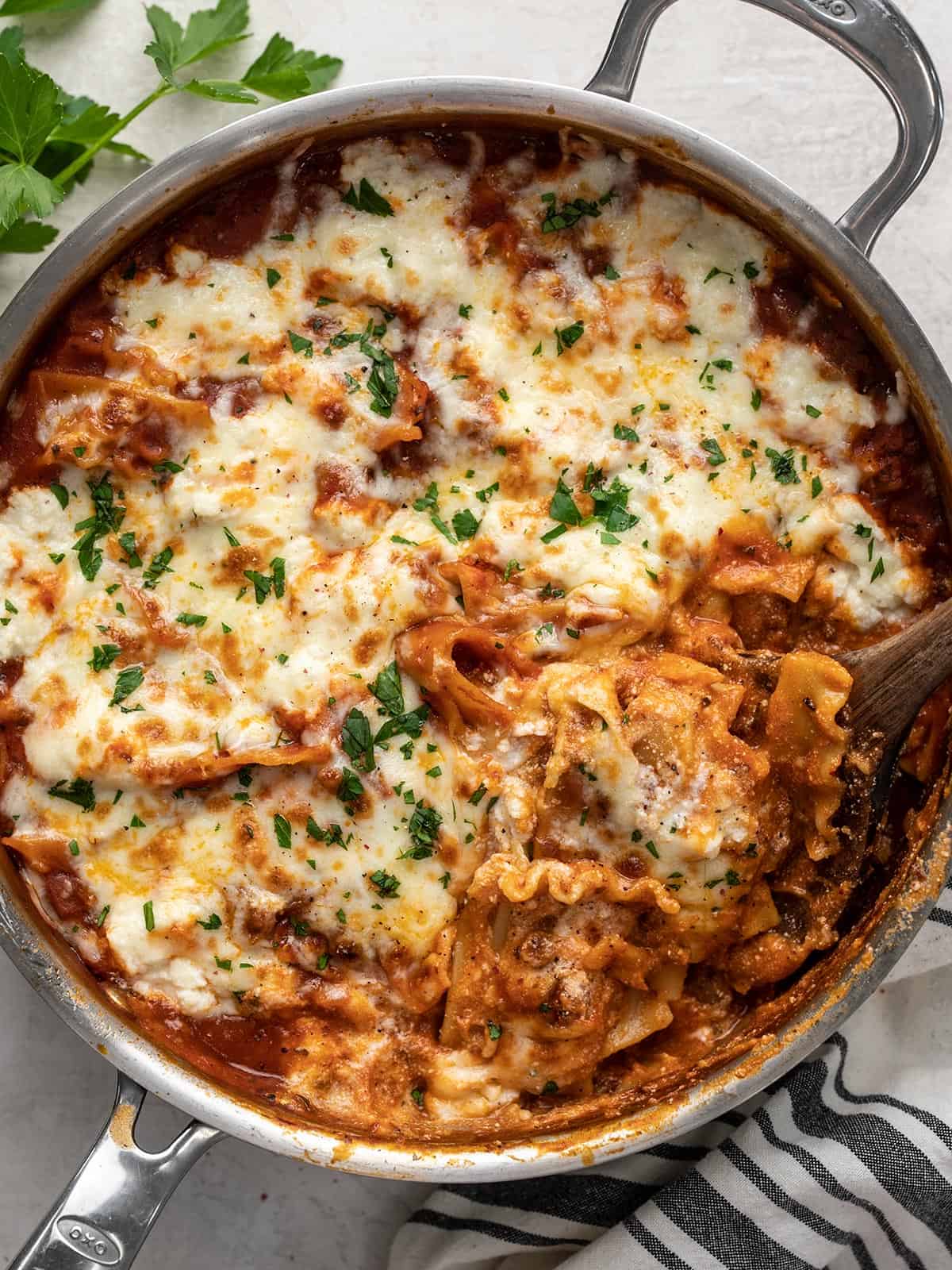 Overhead view of skillet lasagna with a spoon digging into the skillet.