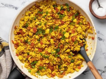 Overhead view of tofu scramble in a skillet with a spatula.