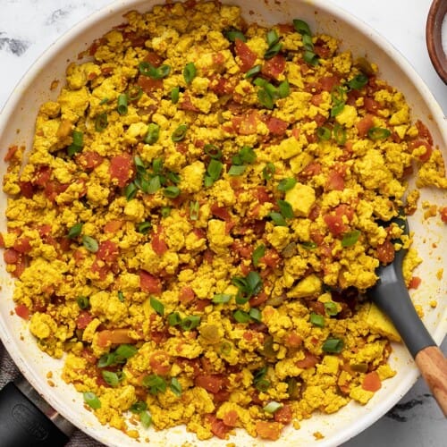 Overhead view of tofu scramble in a skillet with a spatula.