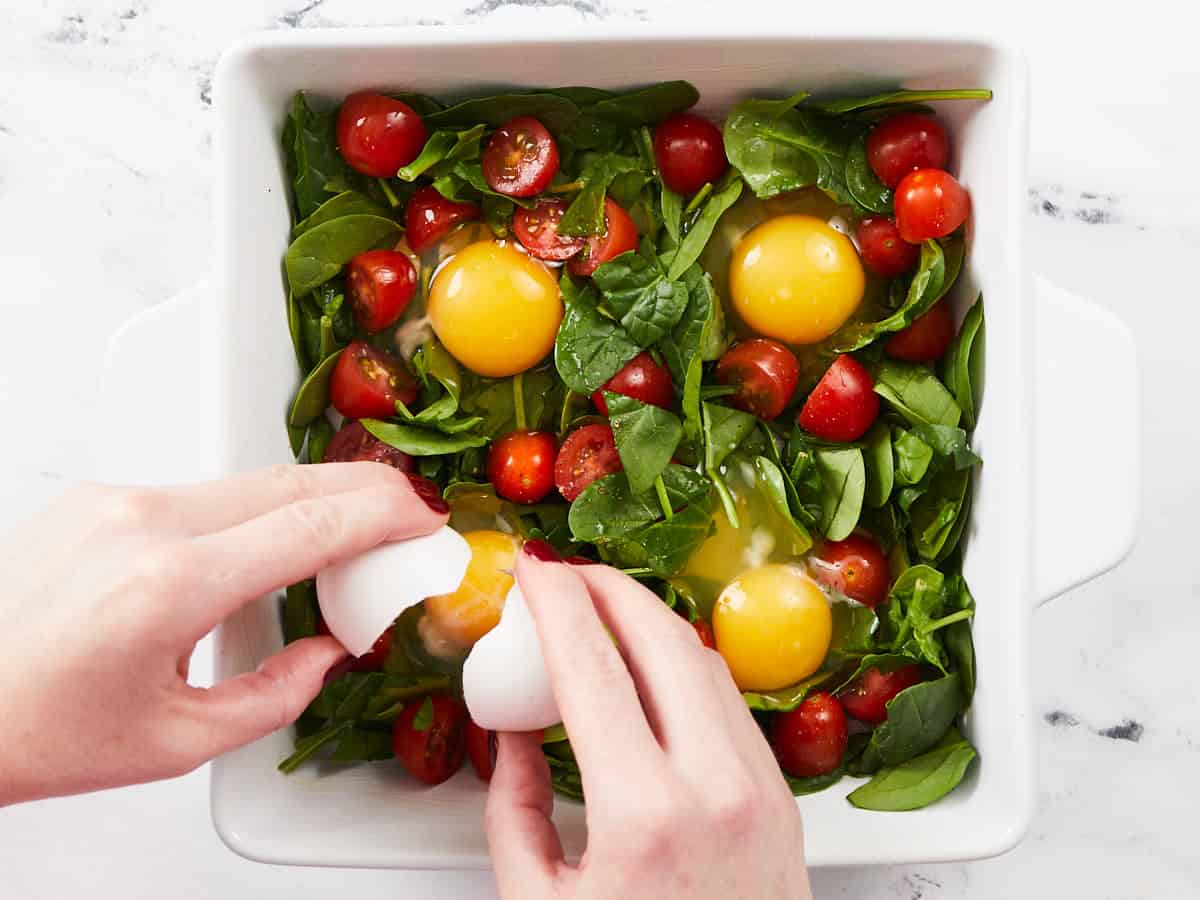 Eggs being cracked into the casserole dish.