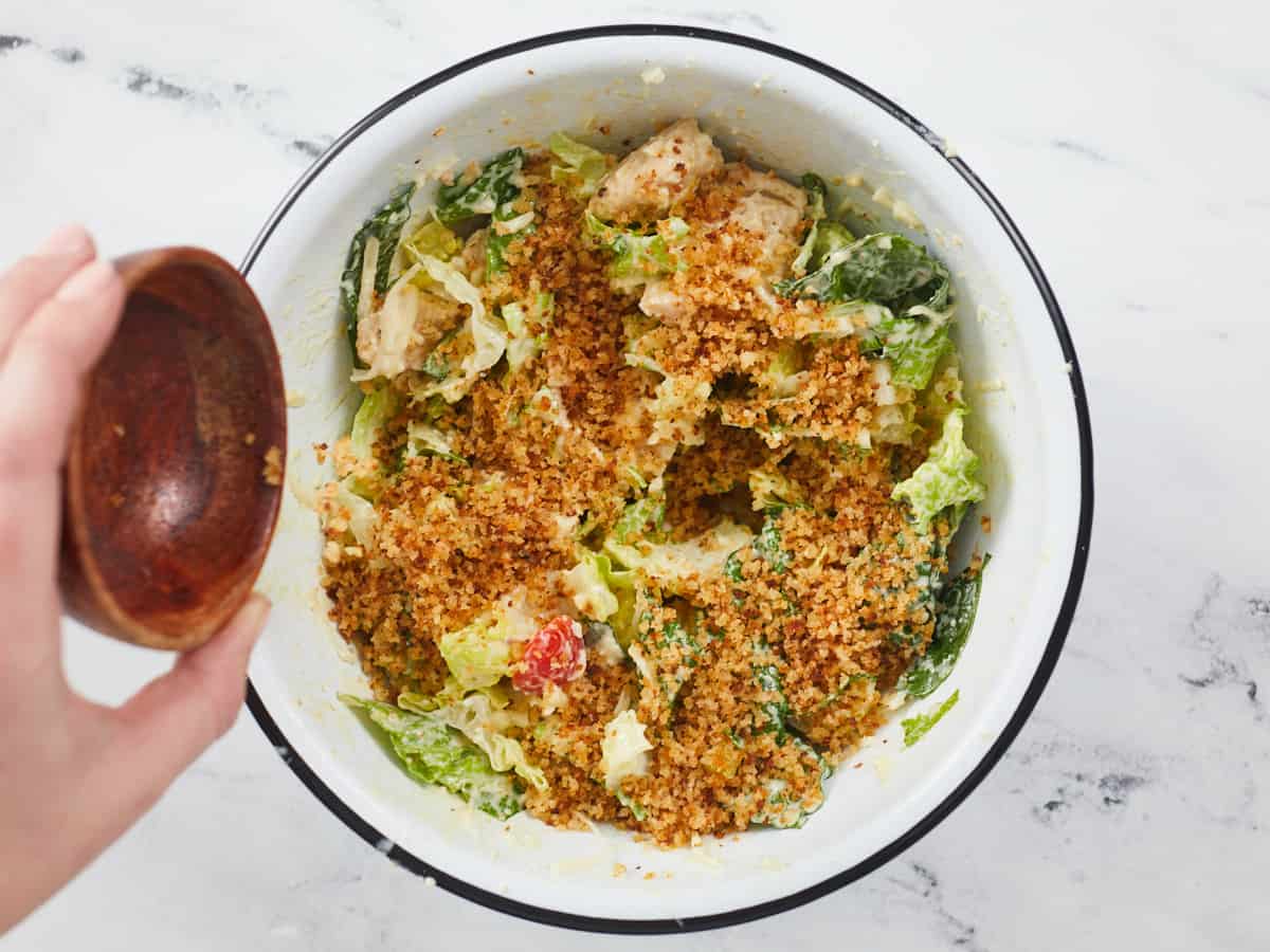 Buttered Breadcrumbs being added to the salad bowl.