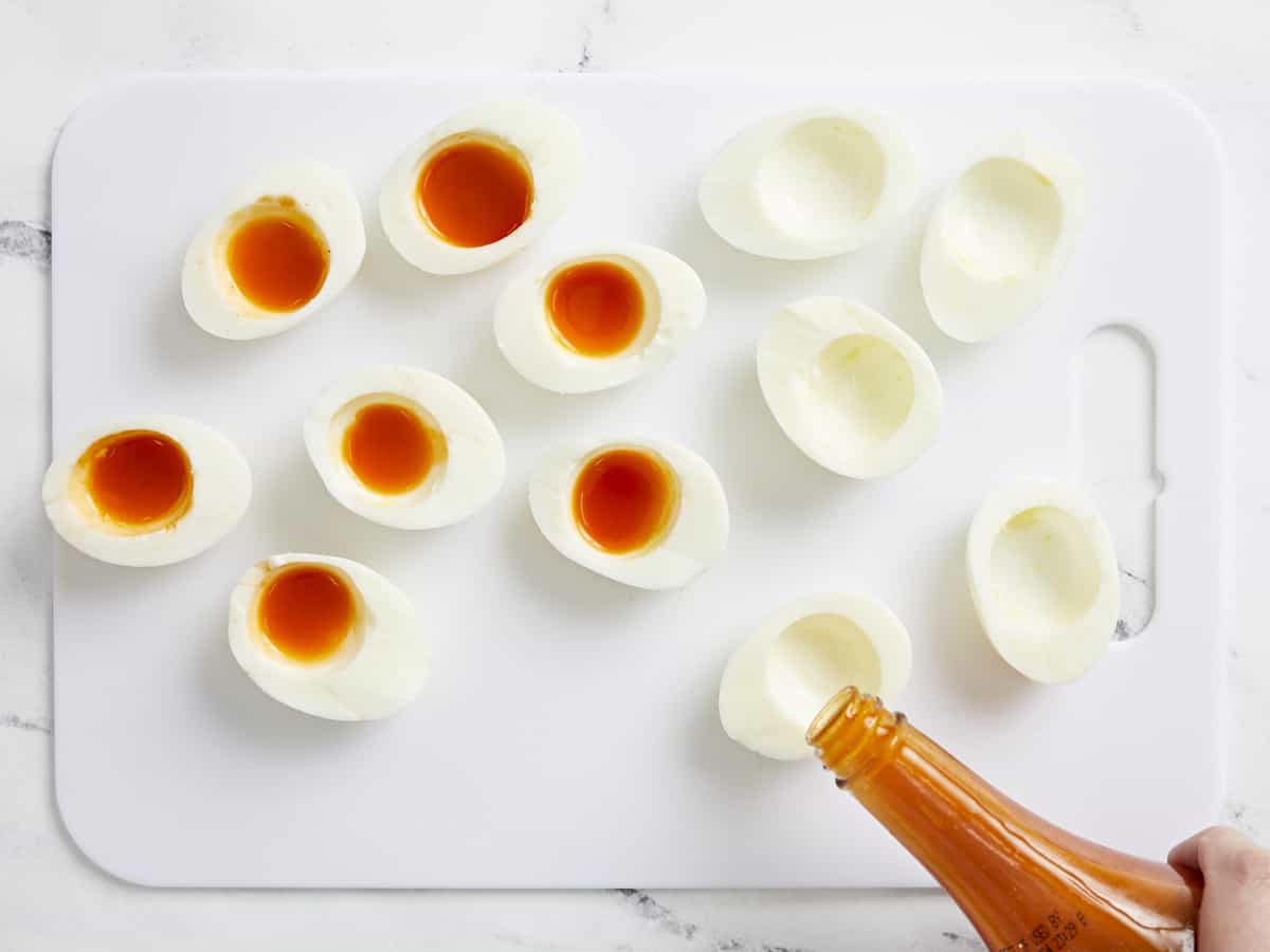 Overhead shot of finished Nashville Hot Deviled Eggs being filled with hot sauce.