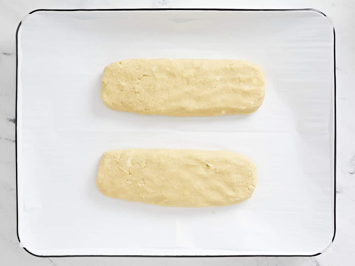 Divided and shaped biscotti dough on a baking sheet.