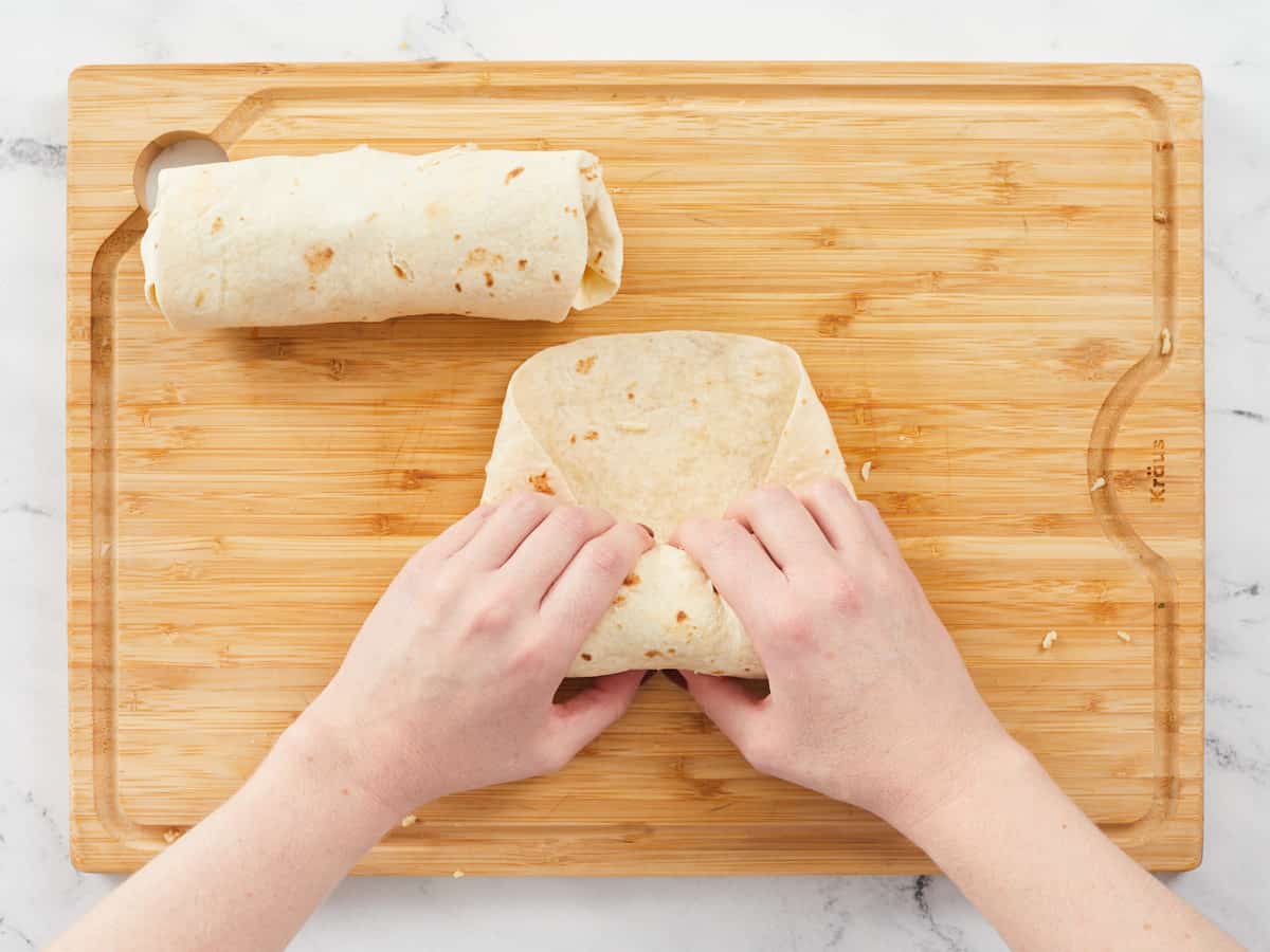 Chicken Caesar wraps being folded and wrapped.