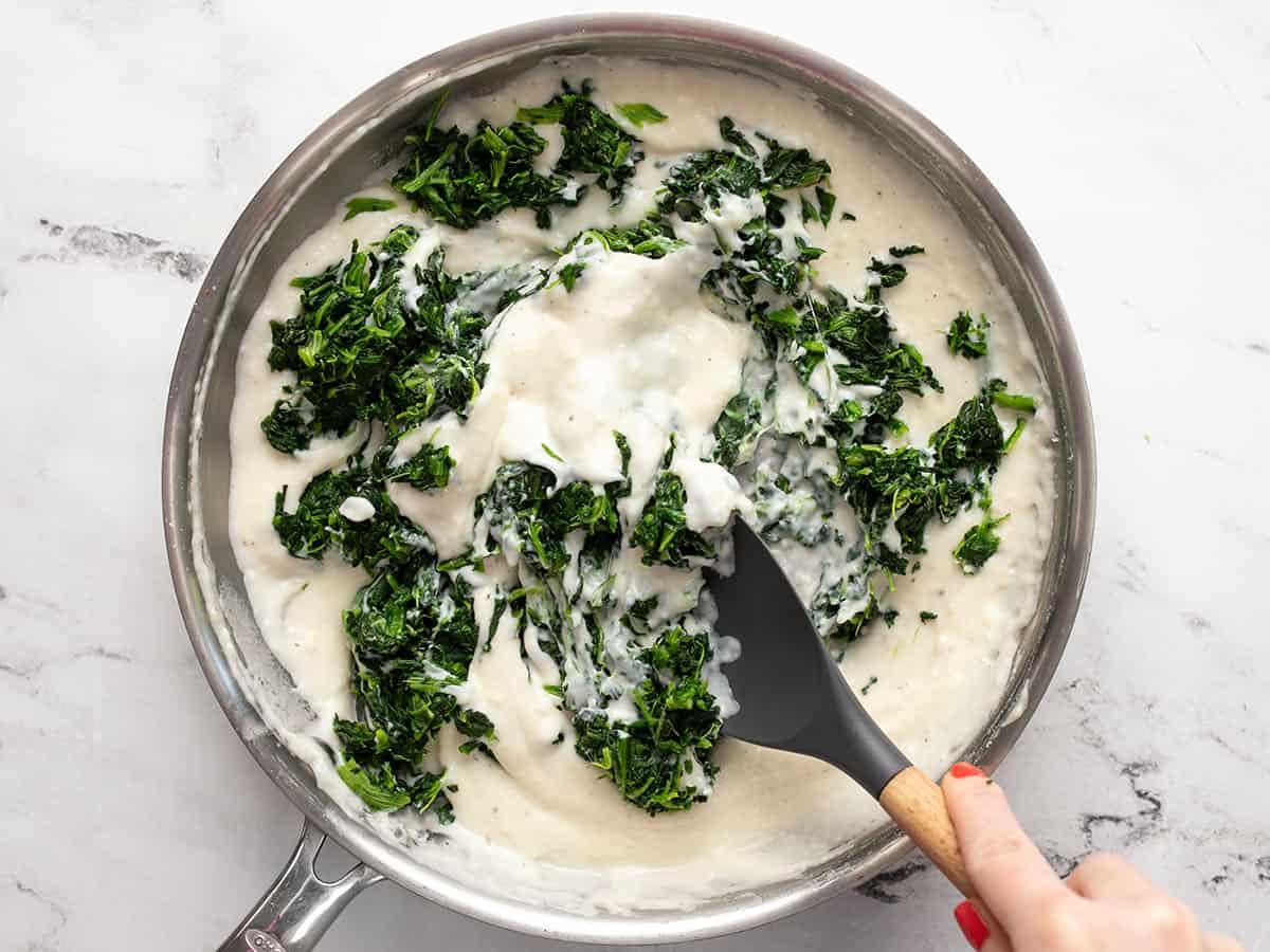 Spinach being stirred into the white sauce.