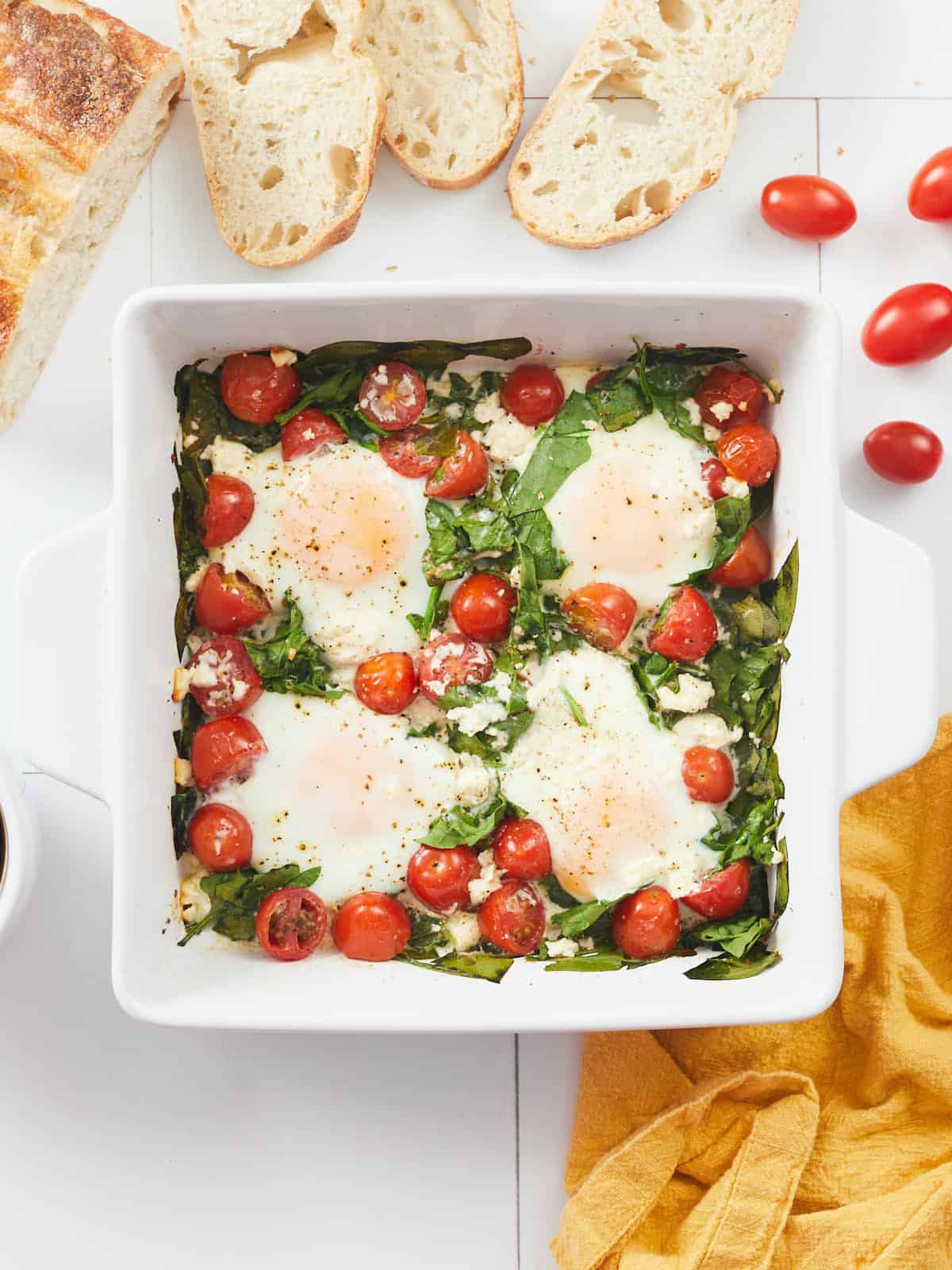 Finished baked eggs in the casserole dish with bread on the side.