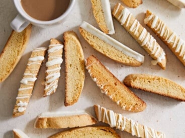 Decorated biscotti scattered next to a coffee cup.