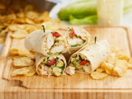 Chicken Caesar wraps cut and stacked together on a wooden cutting board.