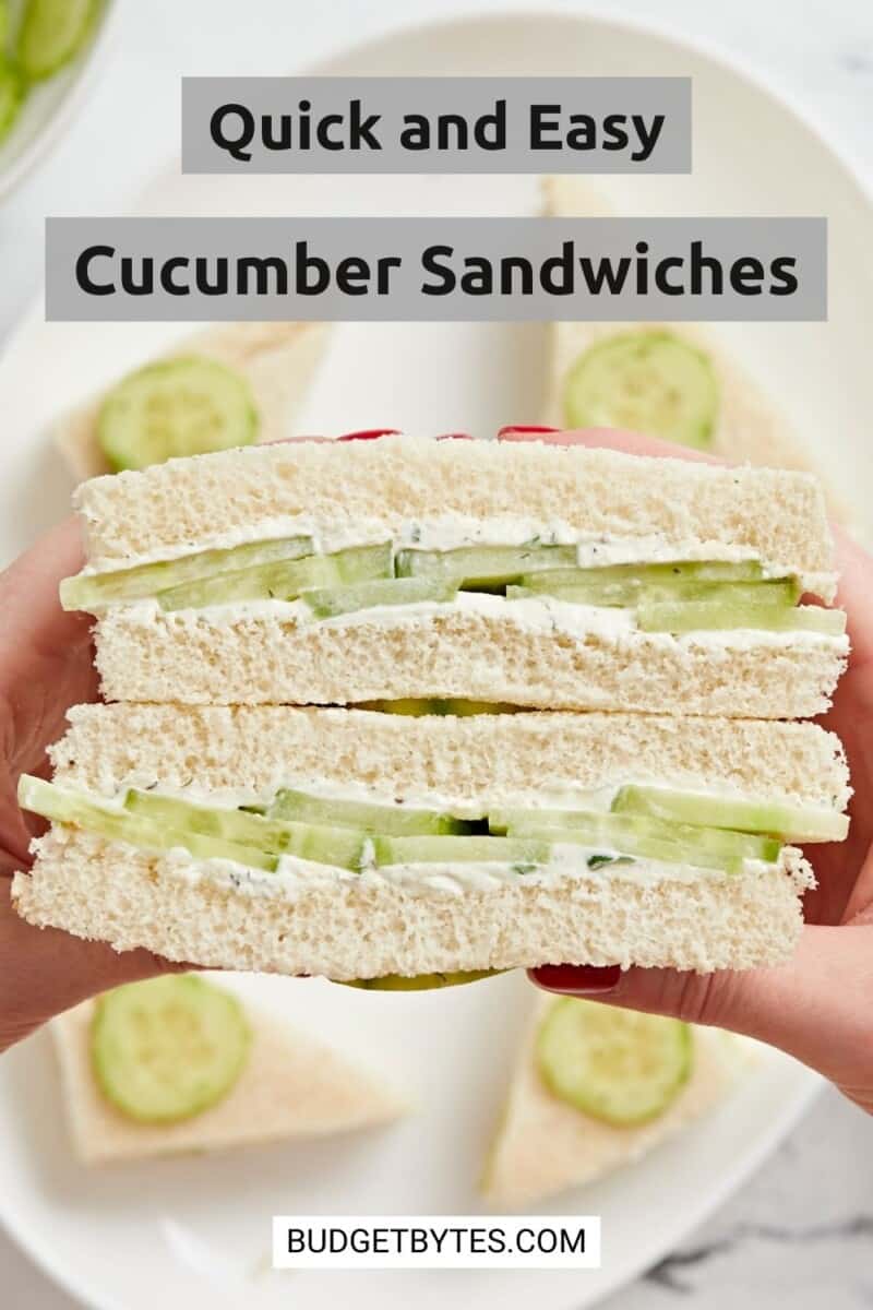 Close up view of a hand holding stacked cucumber sandwiches.