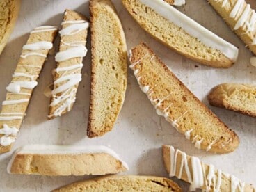 Scattered biscotti on a surface with a cup of coffee.