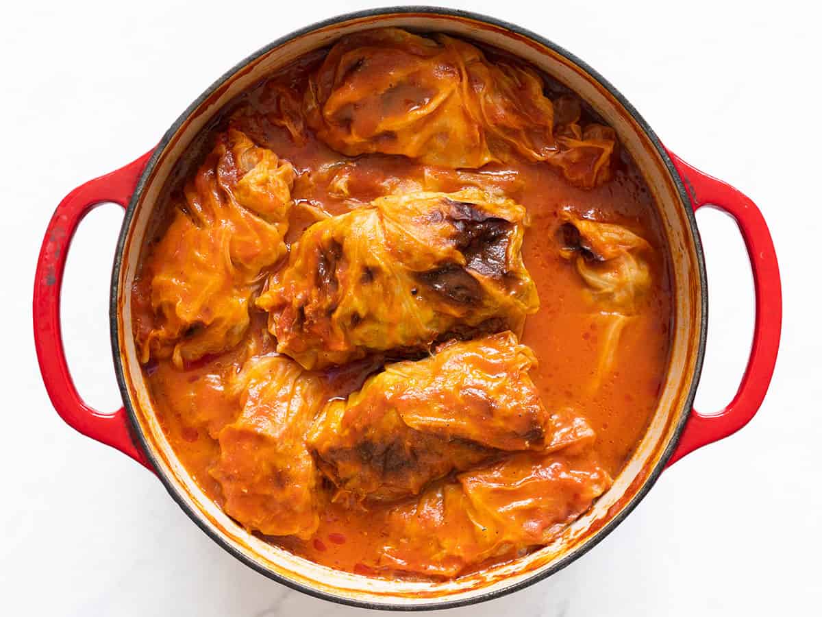 Overhead view of cooked cabbage rolls with tomato sauce in a dutch oven.