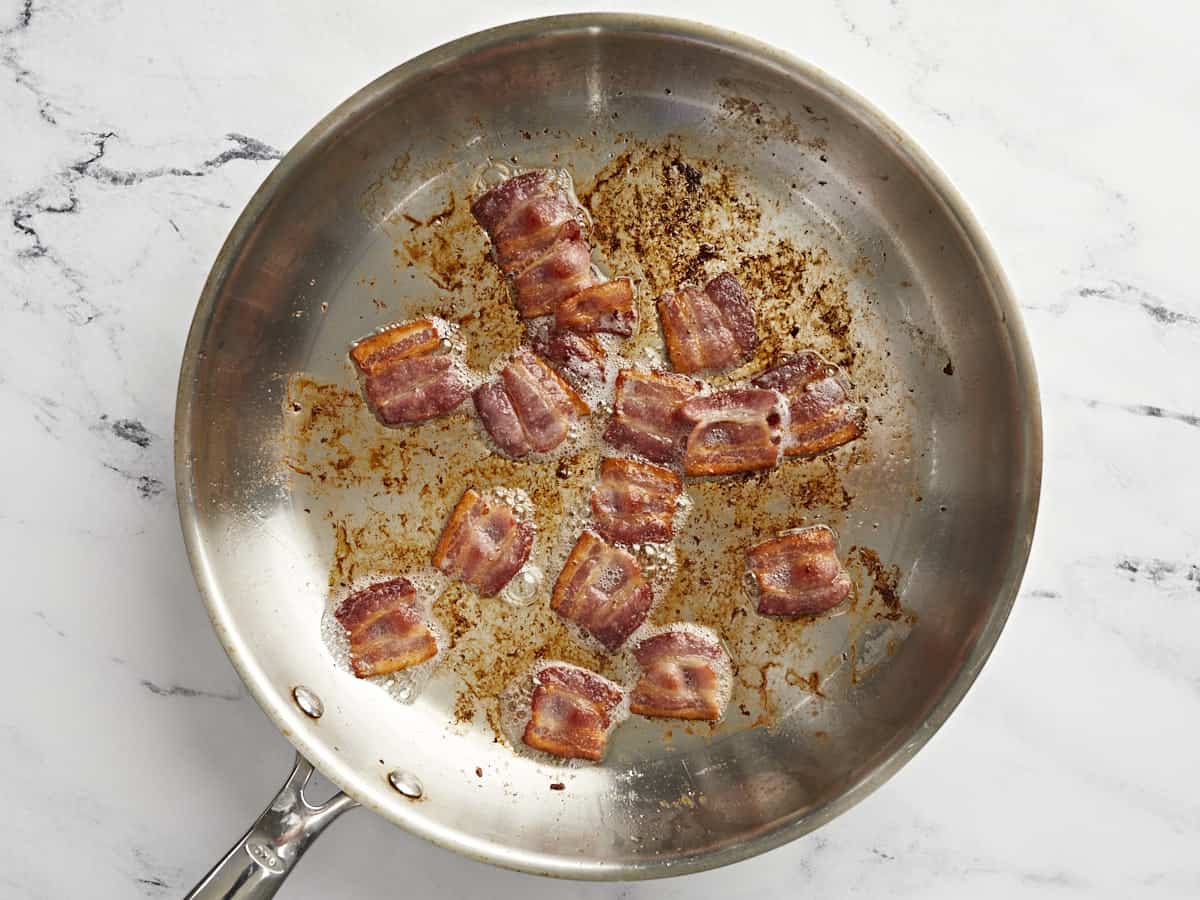 Cooked bacon pieces in a skillet.