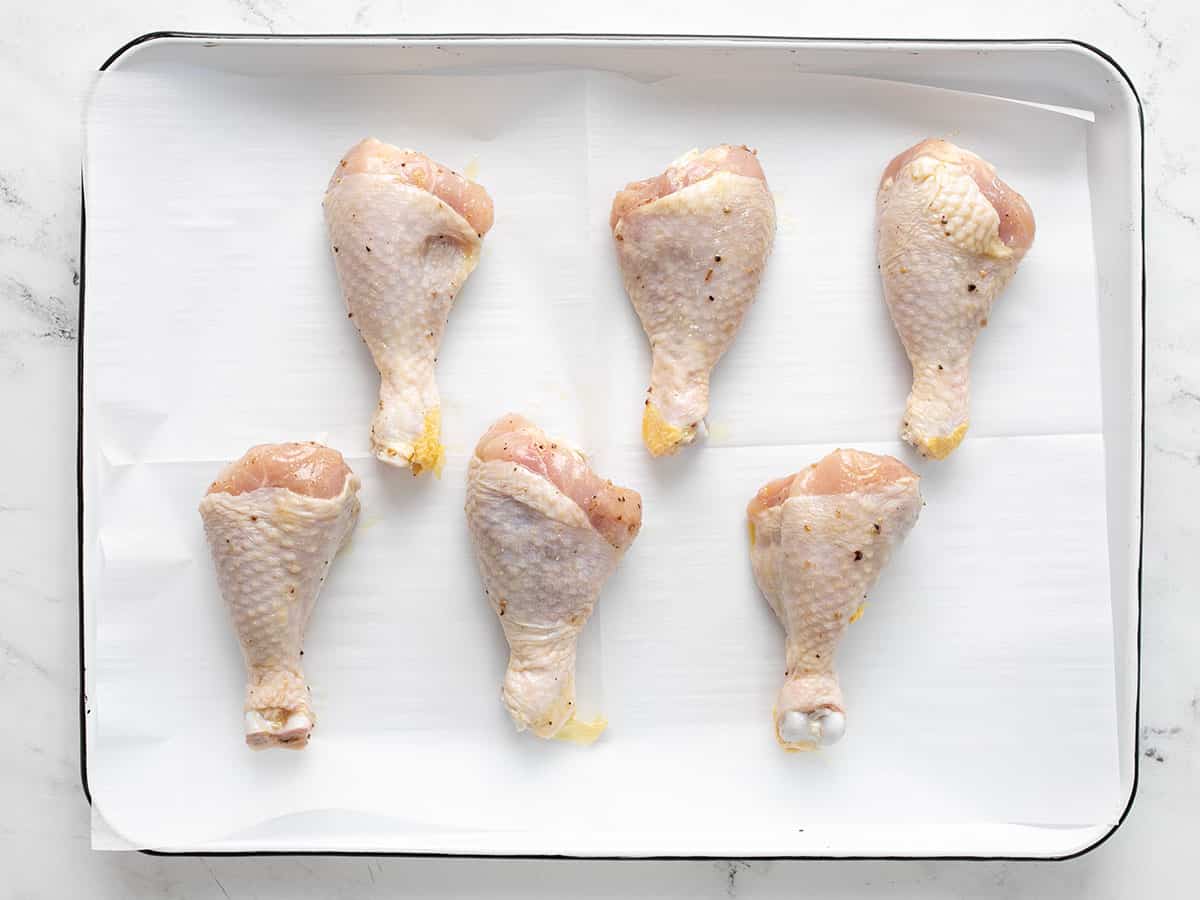 Chicken drumsticks on a prepared baking sheet ready to be cooked.