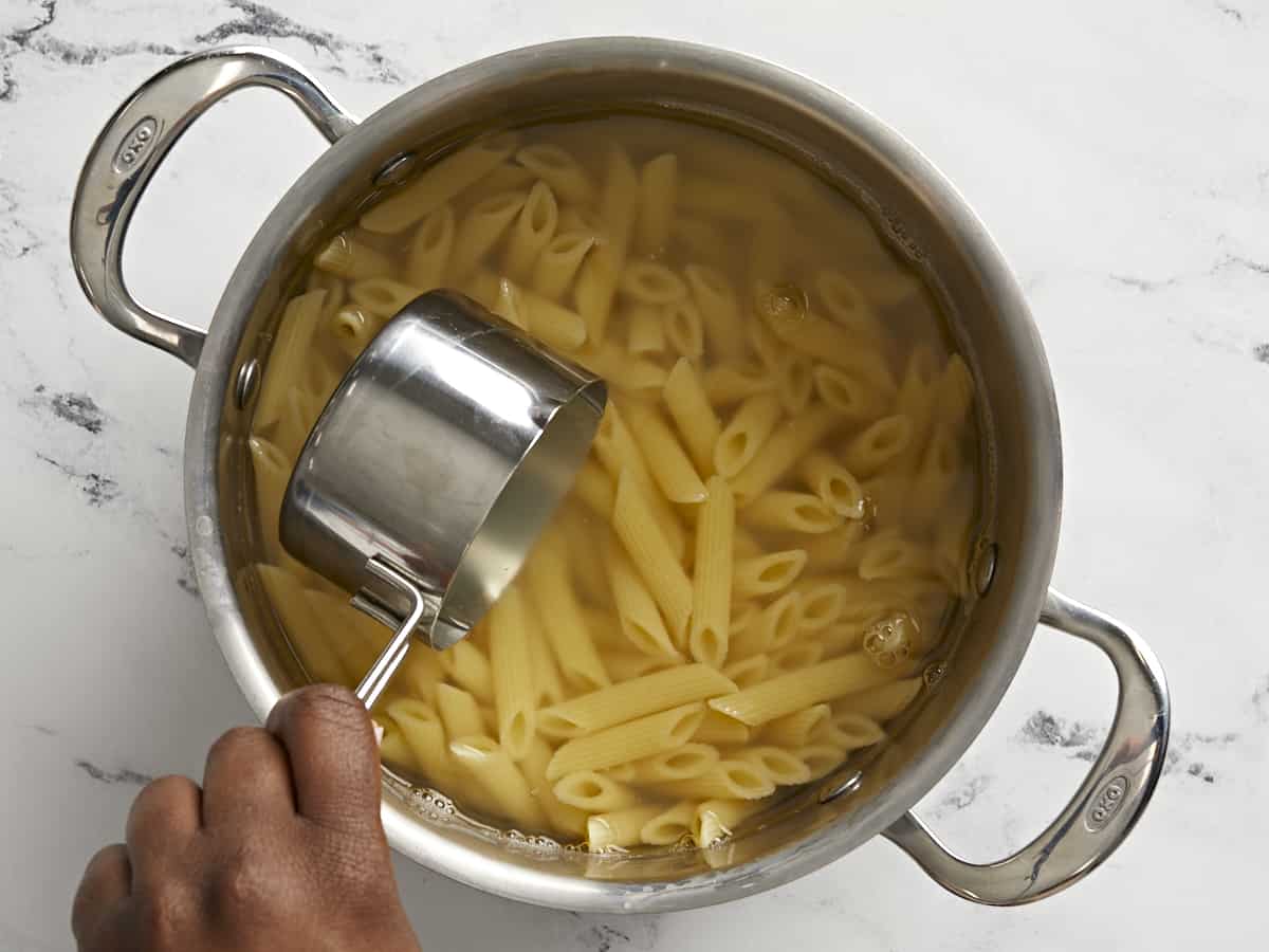 Pasta water being removed from a pot of boiling pasta.