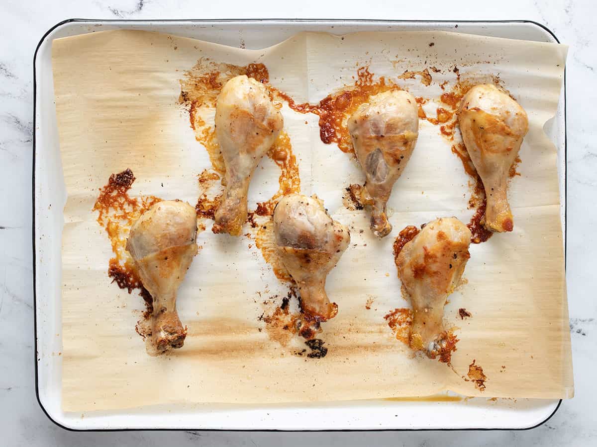 Baked chicken drumsticks on a baking sheet.
